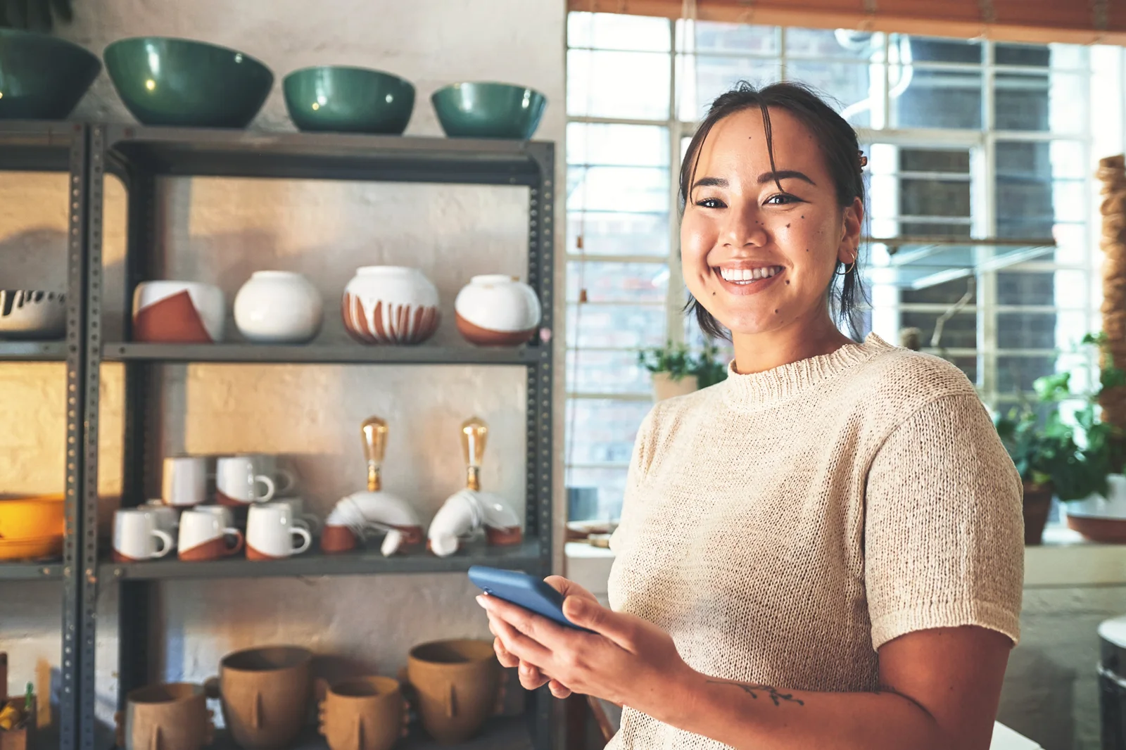 Business owner in her studio checking an invoice payment on her phone