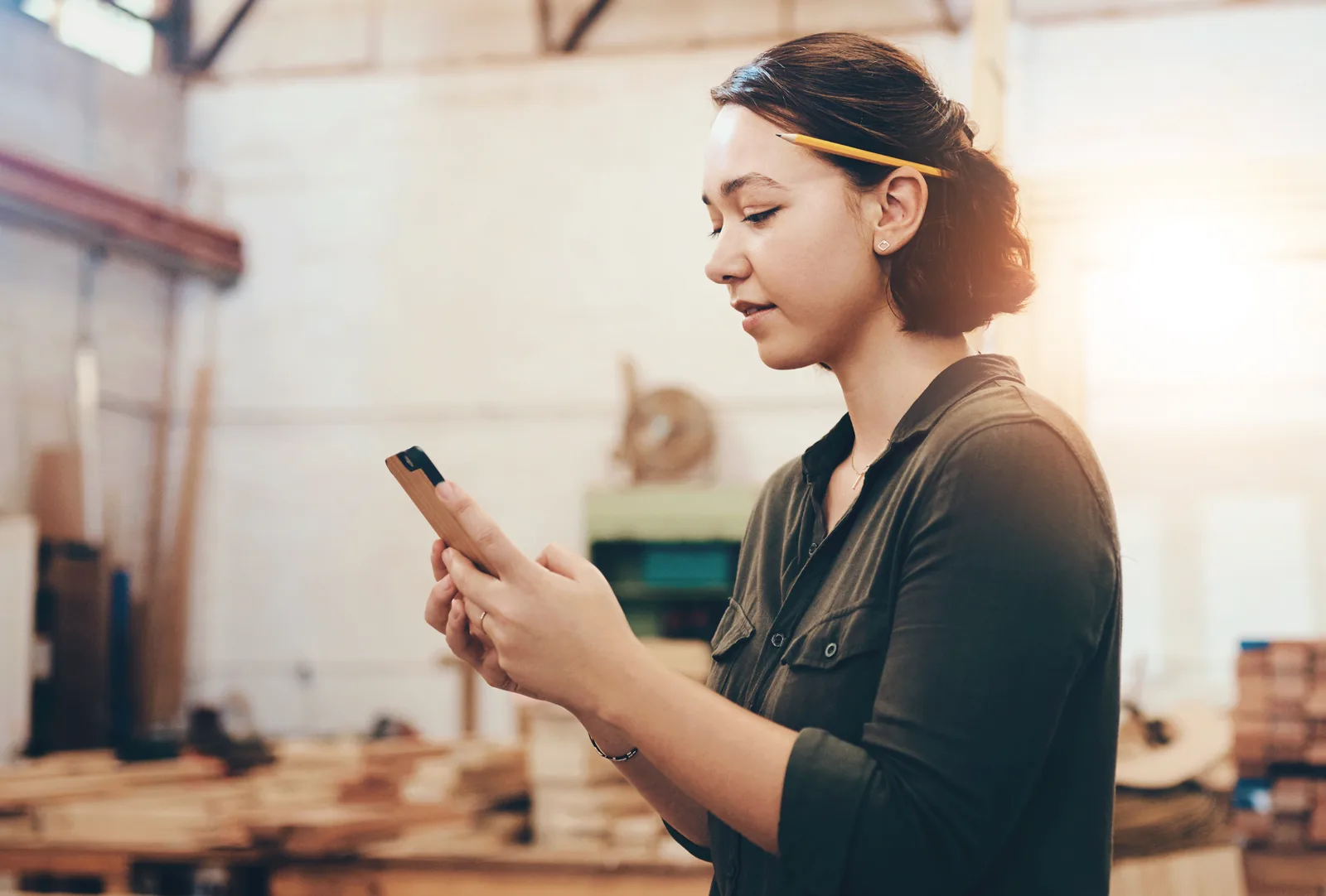 Business owner going over a signed contract on her phone at her workbench